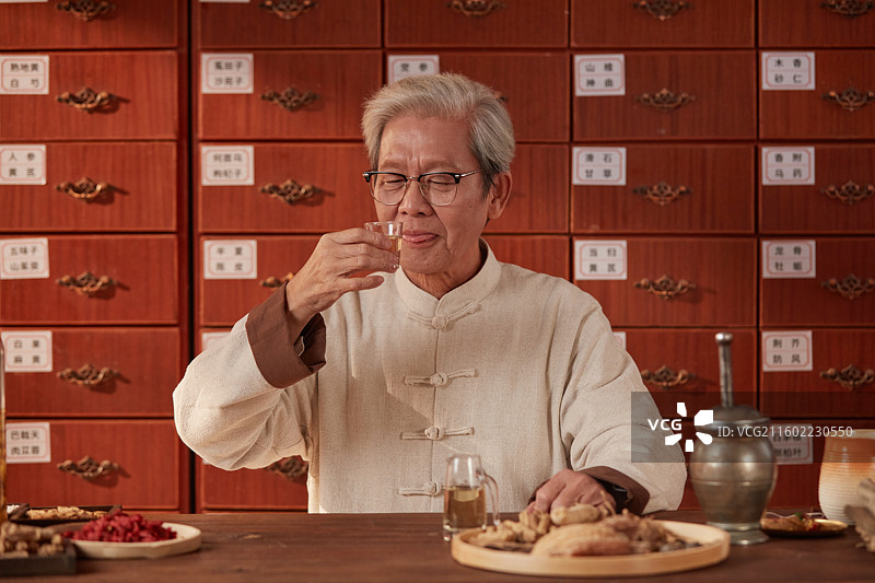 手拿酒杯喝酒的老年医生图片素材