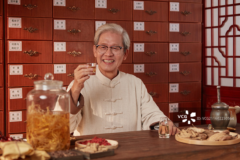 手拿酒杯喝酒的老年医生图片素材