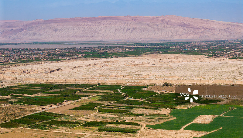 新疆吐鲁番市，高昌故城（航拍视角）；周围是木头沟河绿洲的农田和大棚，远景为火焰山。图片素材