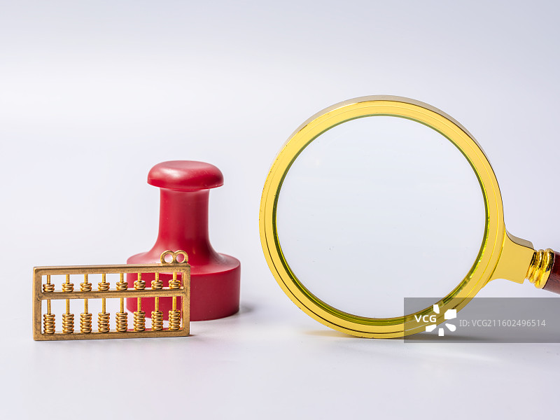 小型金色放大镜、红色印章、铜算盘与白色背景留白图片素材