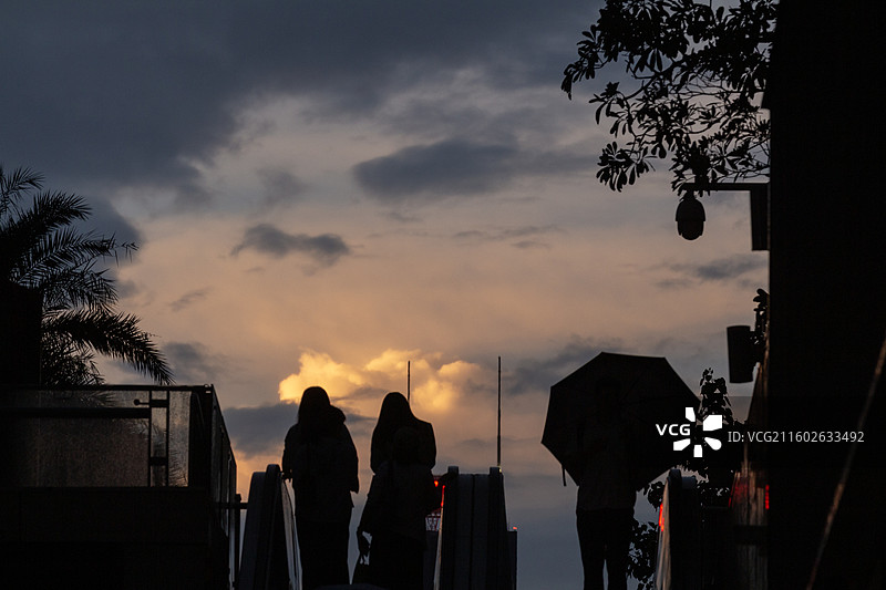 秋天雨后初晴日落时分广州花城汇广场城市戏剧化天空背景电梯上的人物剪影都市风光图片素材