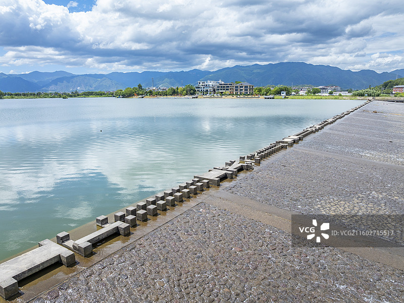 仙居皤滩古镇旁，湖畔堤坝延伸，水面平静，远山含翠，自然与人文交融。图片素材