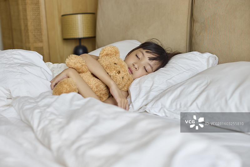 小女孩抱着玩具熊睡觉图片素材