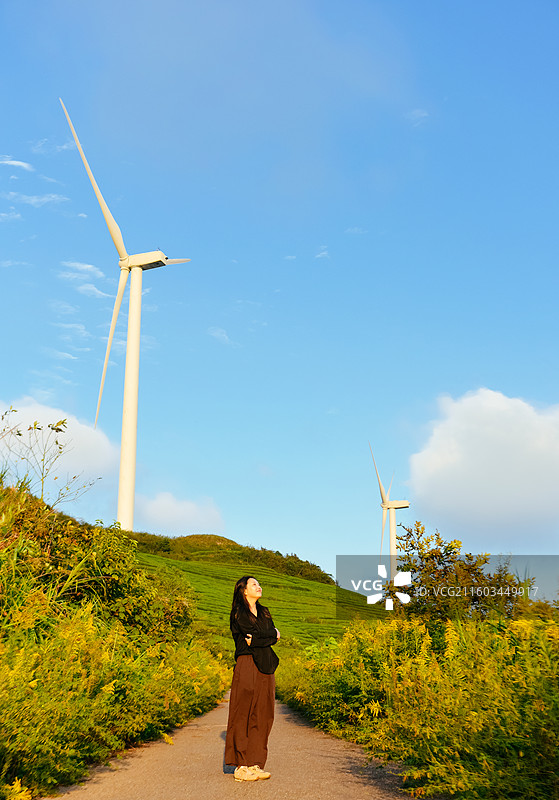 一位亚洲女性在浙江宁波鄞州区横溪镇白岩山山水印最美风车公路欣赏风力发电机组秋日风景图片素材