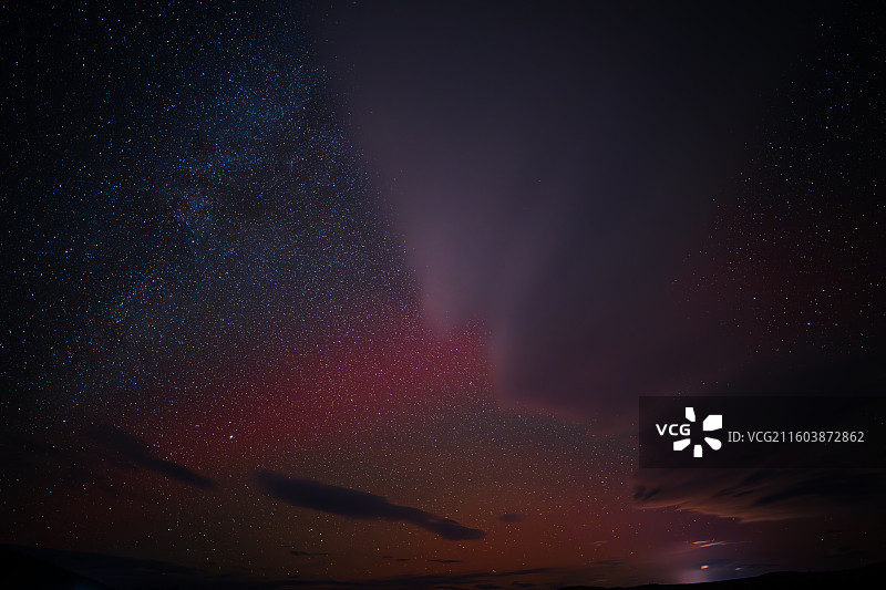 冬天的黑龙江大兴安岭加格达奇北极湖，水面结冰，长曝光拍摄的的星空银河繁星、云层和红紫色的微弱极光图片素材
