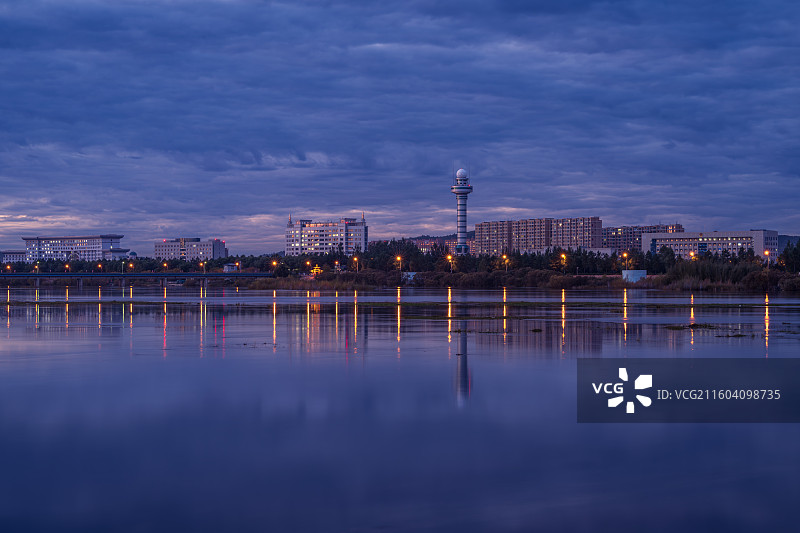 夜幕下傍晚蓝调时刻，大兴安岭加格达奇区市区景观大道建筑群，在甘河平静水面形成倒影，迷人的夜色图片素材