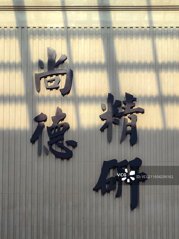 晨光透过玻璃顶子，洒在一面墙上，墙上沾着尚德精研几个大字，很励志图片素材