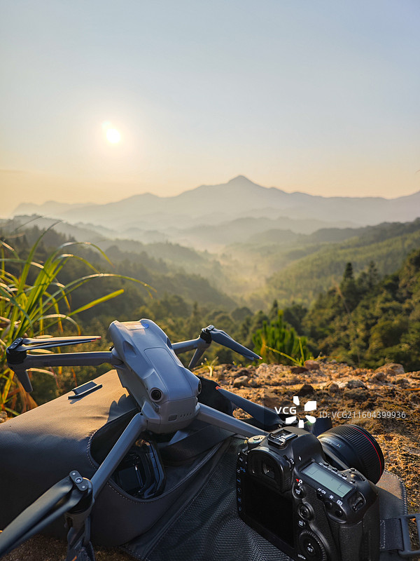无人机与相机静置于山顶远眺层峦叠嶂的山景图片素材