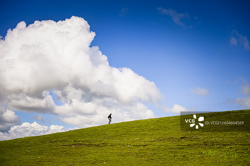 蓝天白云草原下徒步旅行者图片素材
