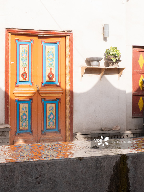 宁静阳光下沙漠古城水池和橘色门图片素材