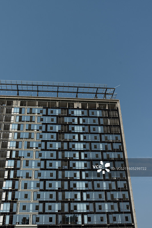 建筑蜕变进行时，钢结构骨架与绿色防护网共舞-装修中的大楼图片素材