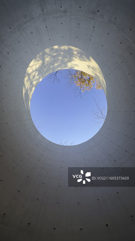 苏州英格玛总部洄归生态美学圆形混凝土结构的低角度仰视，聚焦于顶部的蓝天开口图片素材