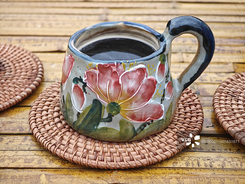 一杯咖啡竹子桌子草编杯垫陶瓷马克杯彩绘荷花绽放图片素材