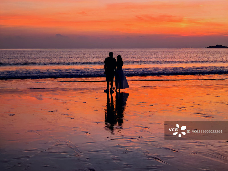 潮汐作证，双影成诗 夕阳熔金，滩涂铺就镜面。双影倒映其中，似时光落款。浪花为证，晚风为媒。图片素材