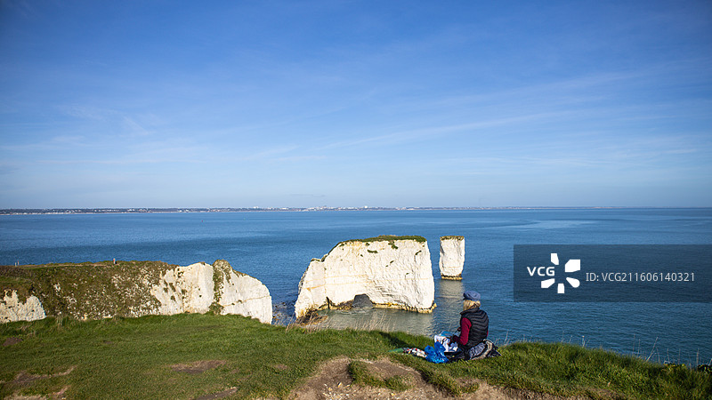 英国老哈利岩坐在海边悬崖上的人的后视图图片素材