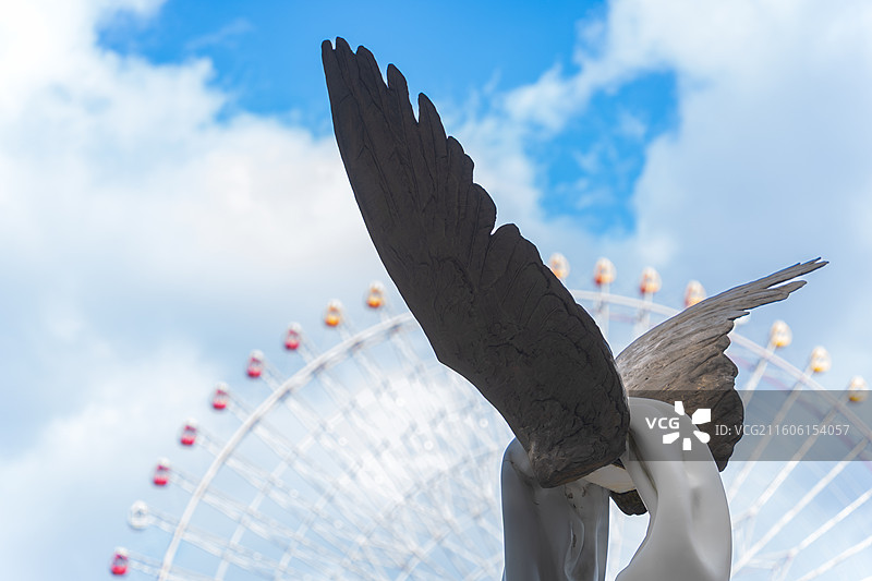 日本横滨摩天轮背景下的现代翅膀雕塑图片素材
