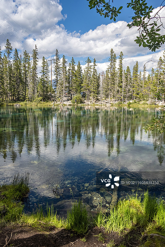 加拿大落基山脉Canmore镇Grassi湖，湖水清澈见底，森林倒影其间，自然宁静。图片素材