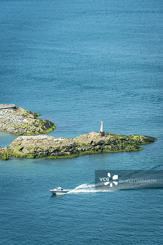 温哥华马蹄湾，游艇驶过灯塔礁石，碧蓝海水与海岸线构成绝美海景。图片素材