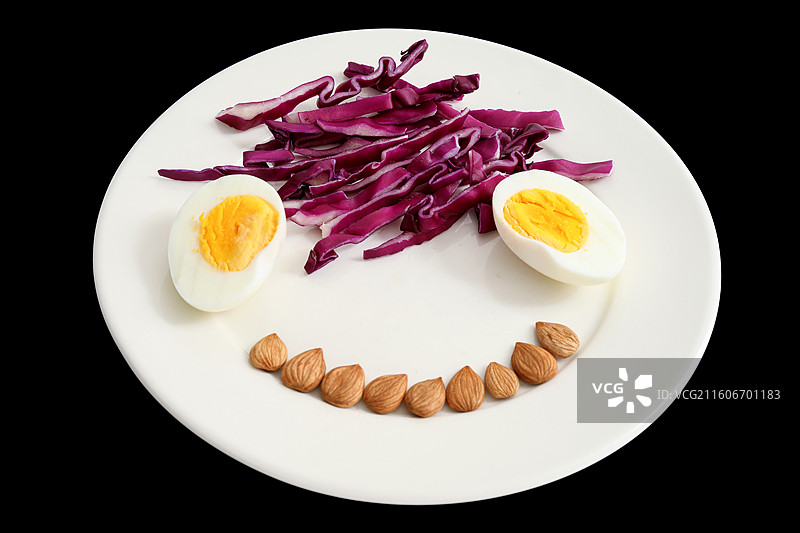 黑色背景上的一盘子营养健康早餐鸡蛋紫甘蓝坚果特写图片素材