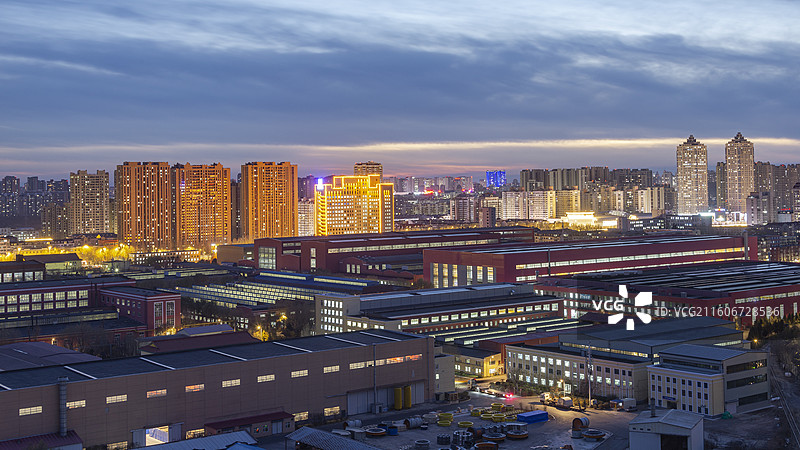 哈尔滨电机厂厂区蓝调夜色，背景是新建的居住区和城市综合体图片素材