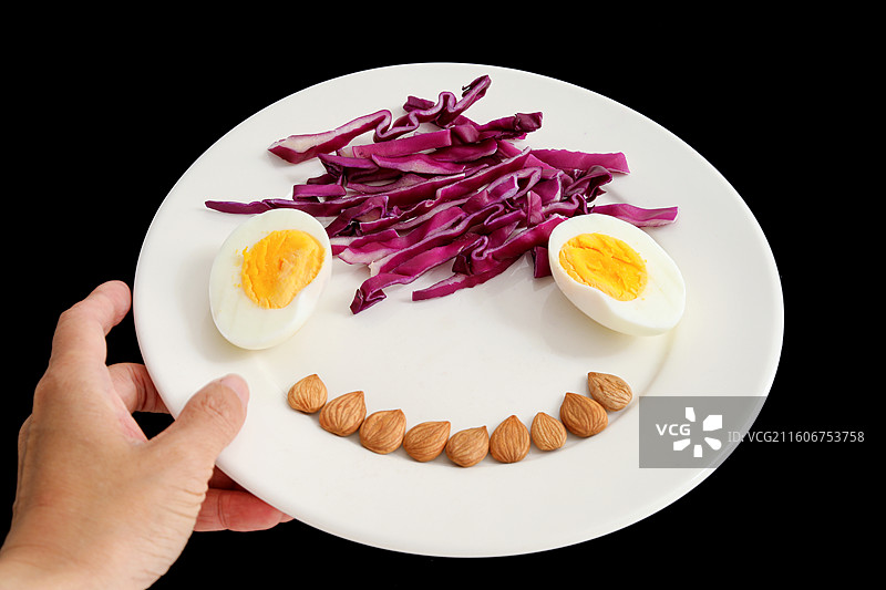 黑色背景上的一盘子营养健康早餐鸡蛋紫甘蓝坚果特写图片素材