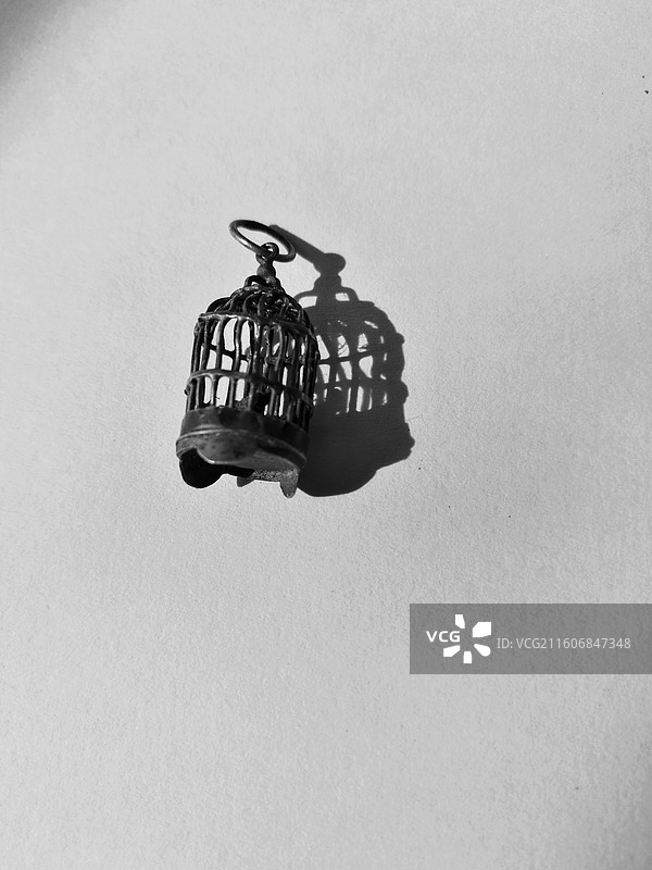阳光下一个小小的老银鸟笼和它的影子。光影图片素材