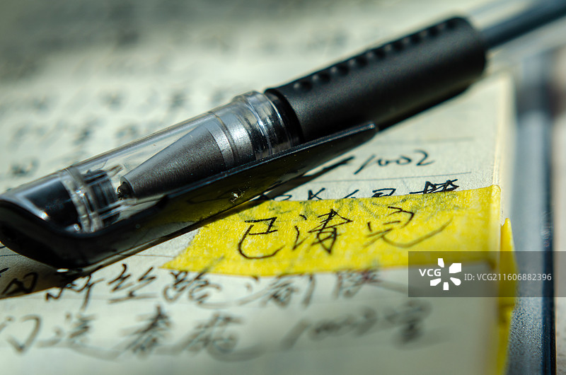 钢笔置于写有字迹的纸张上图片素材