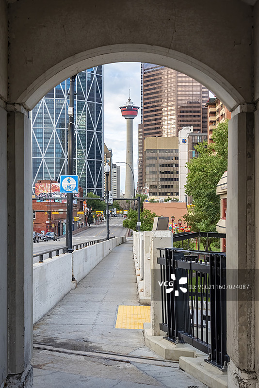 从拱门视角远眺卡尔加里塔，现代建筑林立，街道整洁，展现城市繁华与地标魅力。图片素材