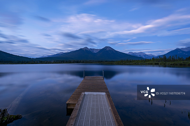 加拿大班夫朱砂湖，木制码头延伸，山脉倒映，天空云朵飘动。图片素材