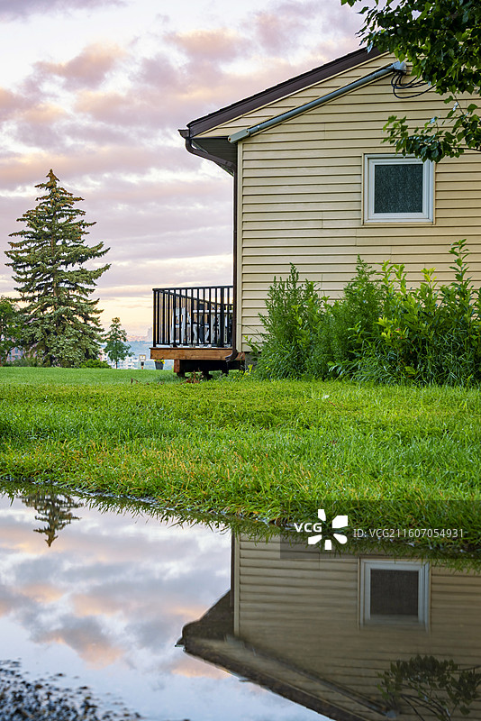 卡尔加里Crescent高地住宅后院，绿草地映水洼倒影，树木房屋相映成趣，自然美景尽收眼底。图片素材