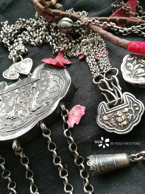 老物件古董老银饰品首饰锁铃铛。黑色老棉布背景传统民俗图片素材