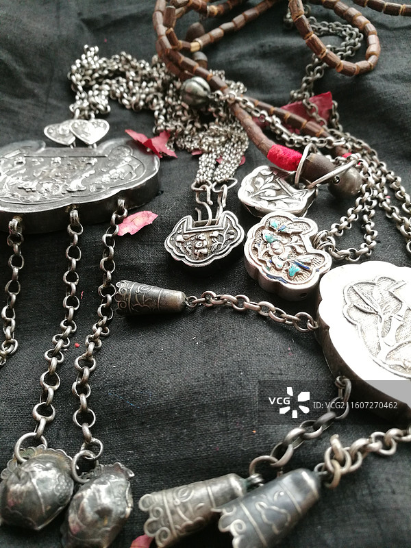 老物件古董老银饰品首饰锁铃铛。黑色老棉布背景传统民俗图片素材