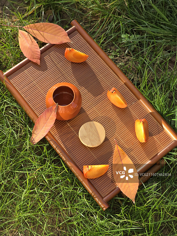 静物草地上茶盘茶叶罐柿子视图图片素材