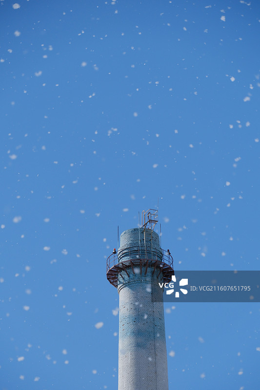 人间四月天。漫天飞舞的杨絮。春天蓝色天空背景下的老式水塔图片素材