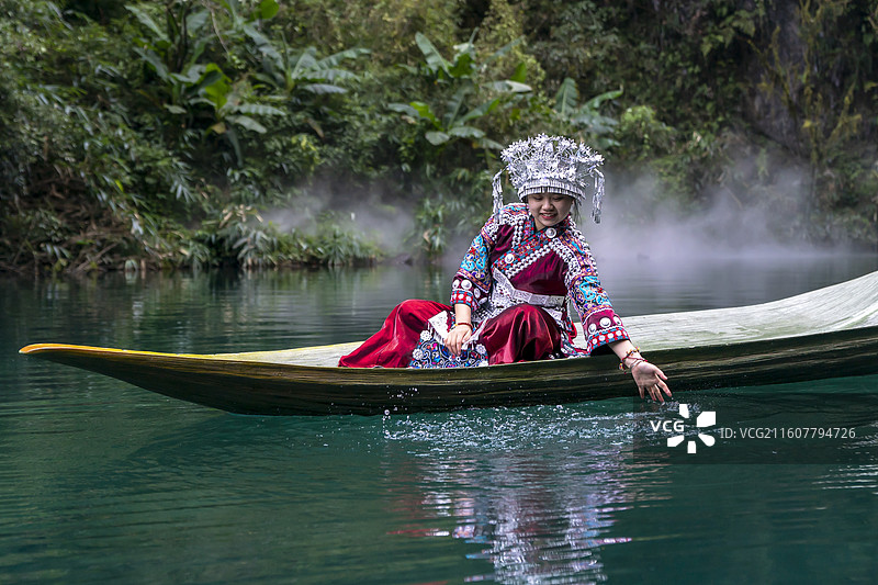一位土家族苗族姑娘在一叶舟上游玩戏水，中国鹤峰屏山峡谷图片素材
