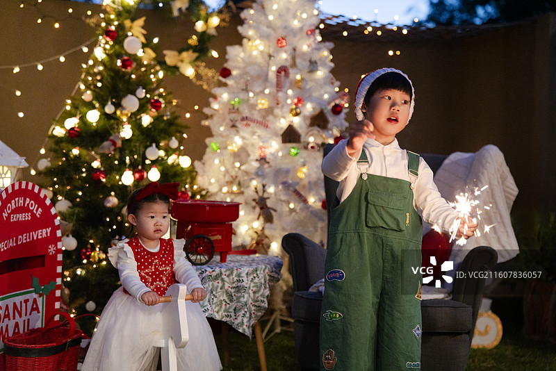 圣诞夜骑白木马的小女孩与点燃焰火棒的小男孩图片素材