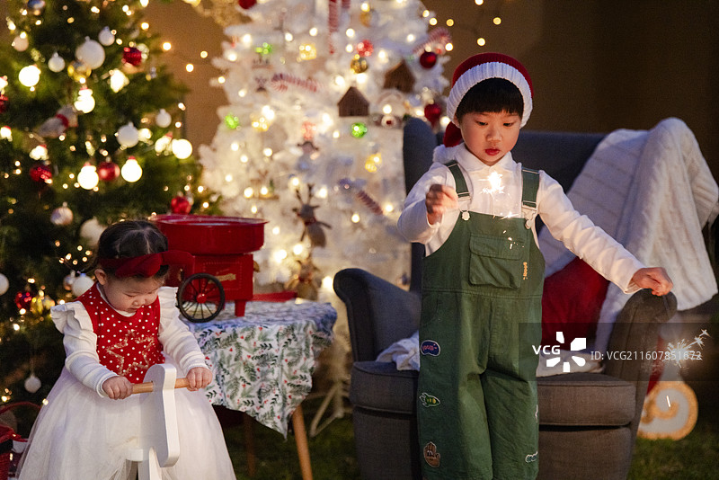圣诞夜骑白木马的小女孩与点燃焰火棒的小男孩图片素材