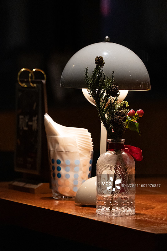 黄色灯光下的酒吧的台灯、桌子和鲜花图片素材