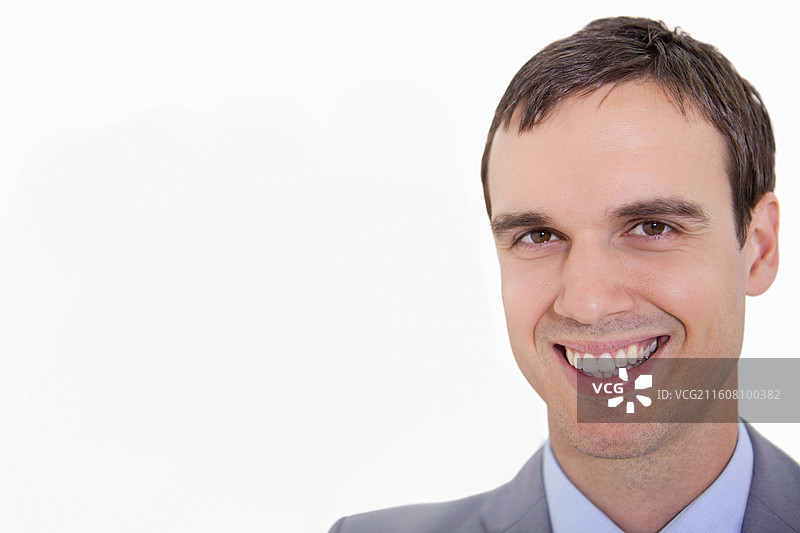 一位穿着灰色西装和浅蓝色衬衫的成年男性，面带微笑，在影棚肖像照中摆姿势，留有复制空间图片素材