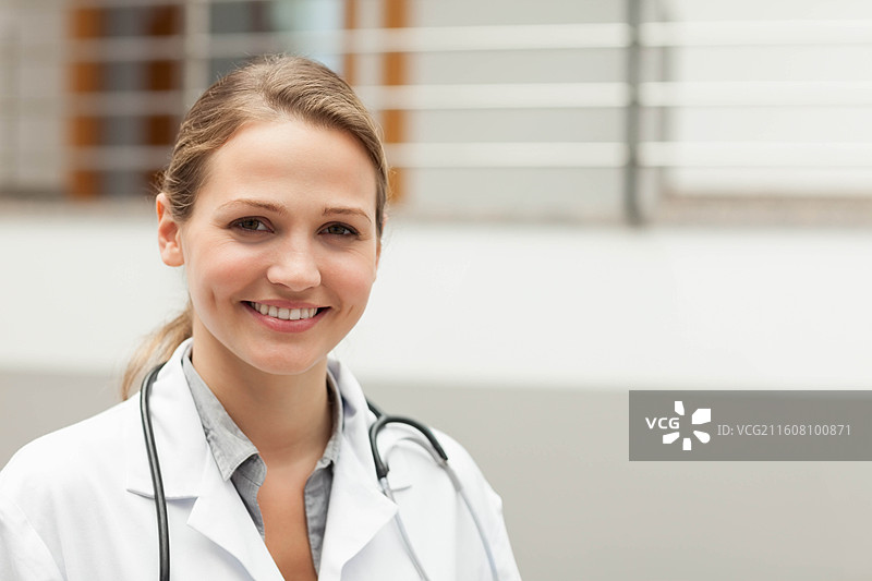 女医生穿着白大褂、领衬衫，戴着听诊器，站在诊所大厅，有复制空间图片素材