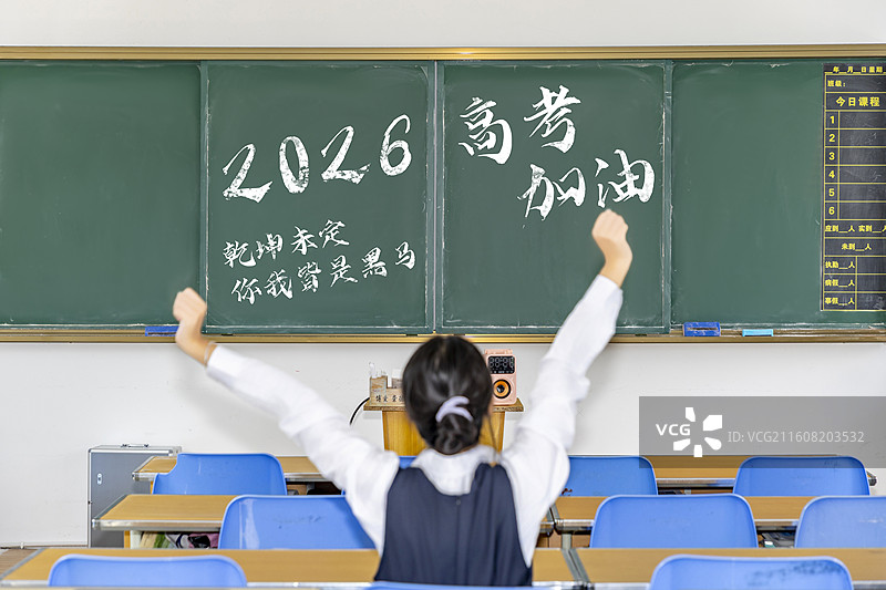 一个女子坐在教室里伸懒腰黑板上写着2026高考加油图片素材