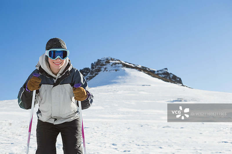 身穿夹克、手持粉色登山杖的女性站在斜坡岩脊附近，可供复制图片素材