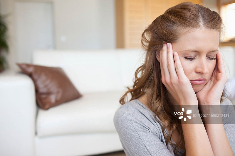 白色的沙发靠墙摆放，配有棕色皮革靠垫，百叶窗过滤着柔和的日光图片素材