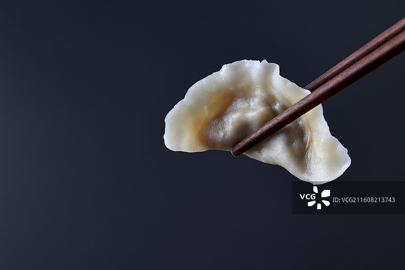 筷子夹起的饺子黑色背景图片素材