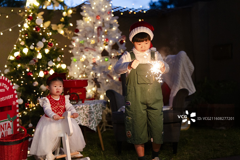 圣诞夜骑白木马的小女孩与点燃焰火棒的小男孩图片素材