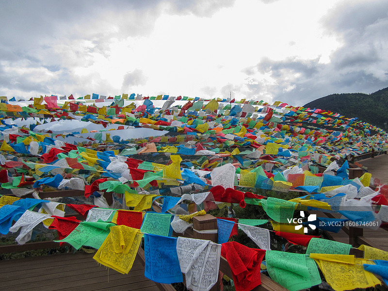 多云下飘动的五彩经幡图片素材