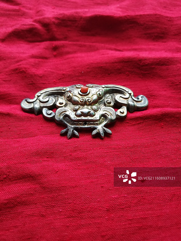 红色背景红布老首饰银饰品。狮虎头辟邪保平安儿童帽饰设计素材图片素材