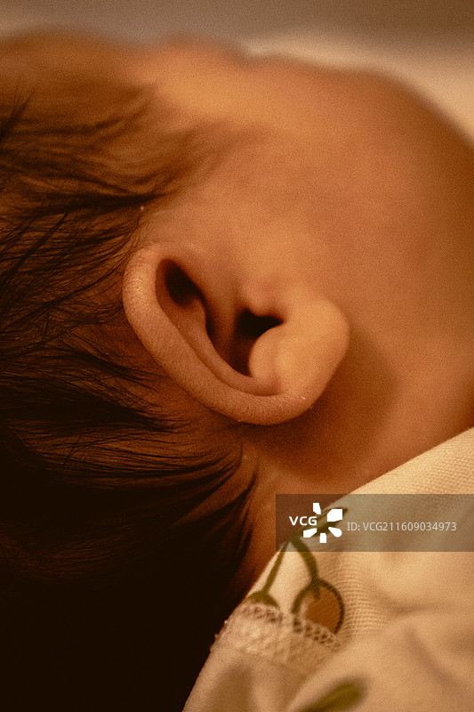 黄色暖色灯光下的胶片感婴儿耳朵局部特写图片素材