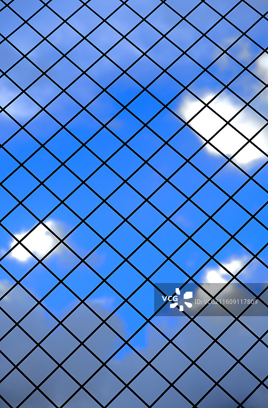 蓝天白云下的铁丝网围栏特写图片素材