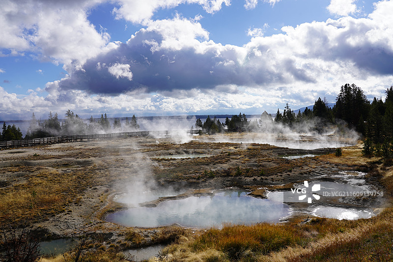 美国黄石公园的秋日美景 加拿大鹅成群结队飞过彩叶林和湖泊 雪山在远方 涌出滚烫泉水的五彩池和日光狂热图片素材